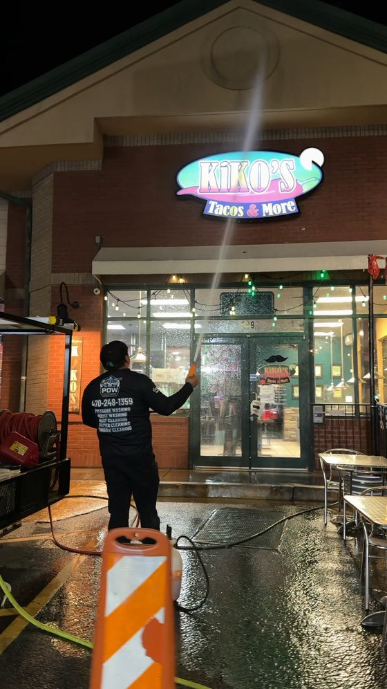 POW crew pressure washing a restaurant storefront at night